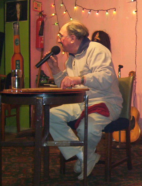 Gordon Cragg seated, placing numbers on a bingo board and talking into a chordless mike